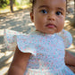 Baby wearing Confetti Print Josie Bubble sitting outdoors with trees in the background