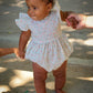 Baby in a floral Josie bubble being held by an adult outdoors
