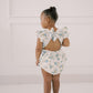 Child wearing a floral romper  with tied back bow back closure