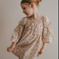 Young girl wearing a floral dress against a plain background