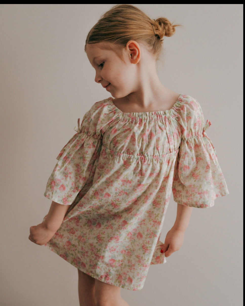 Young girl wearing a floral dress against a plain background