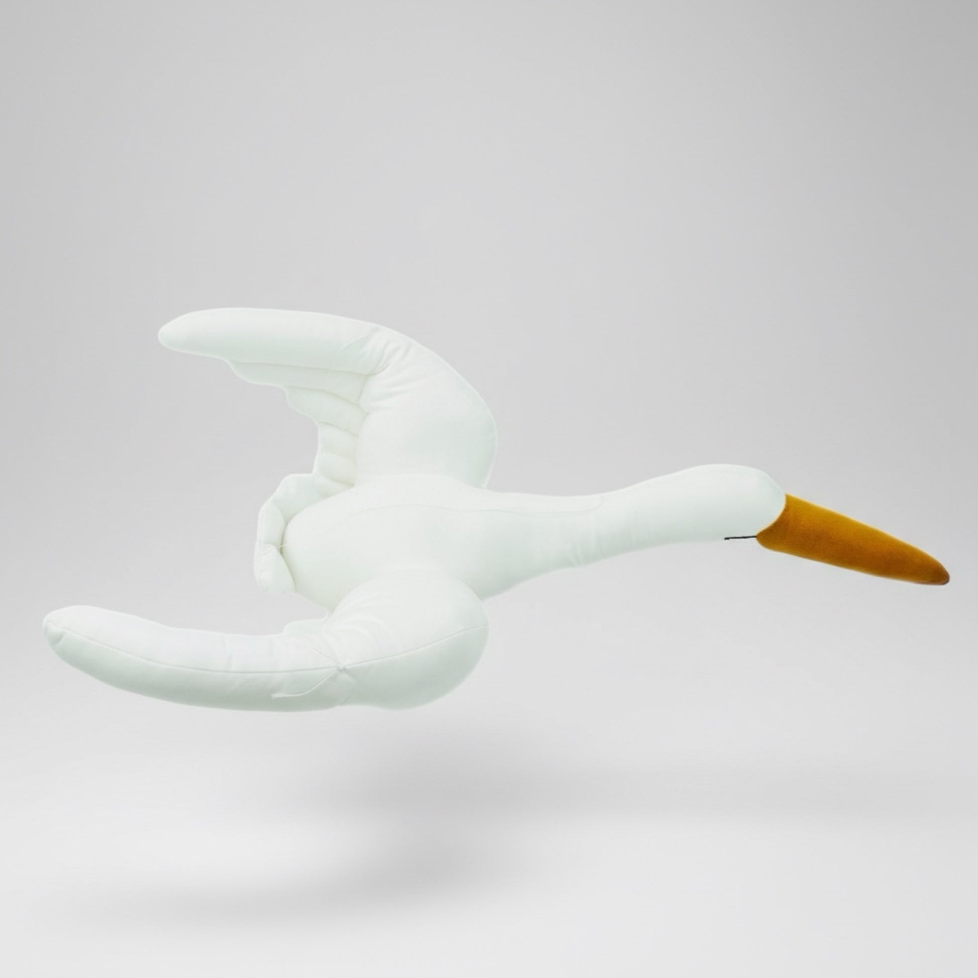 White plush toy swan with a yellow beak on a light gray background
