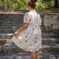 Young girl in a floral dress standing on stone steps outdoors