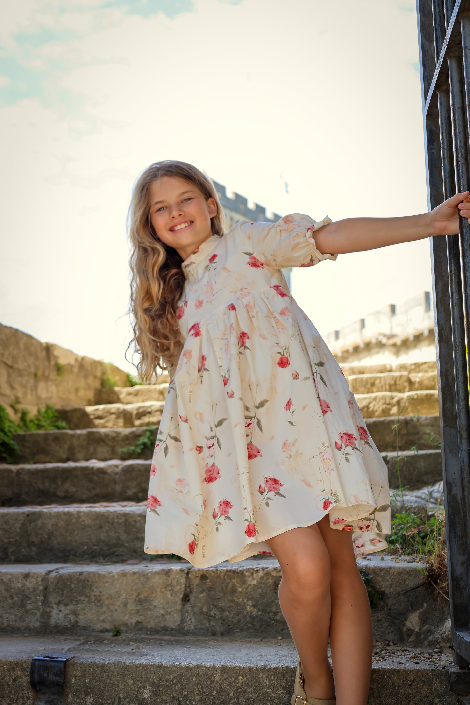 Young girl in a floral dress standing on stone steps outdoors