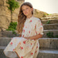 Young girl in a floral dress sitting on stone steps with a castle in the background