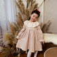 Young girl in a floral dress with pampas grass and white curtains in the background