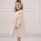 Young girl wearing a floral dress with a white headband against a light background
