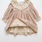 Children's dress with floral pattern and ruffled collar on a white background