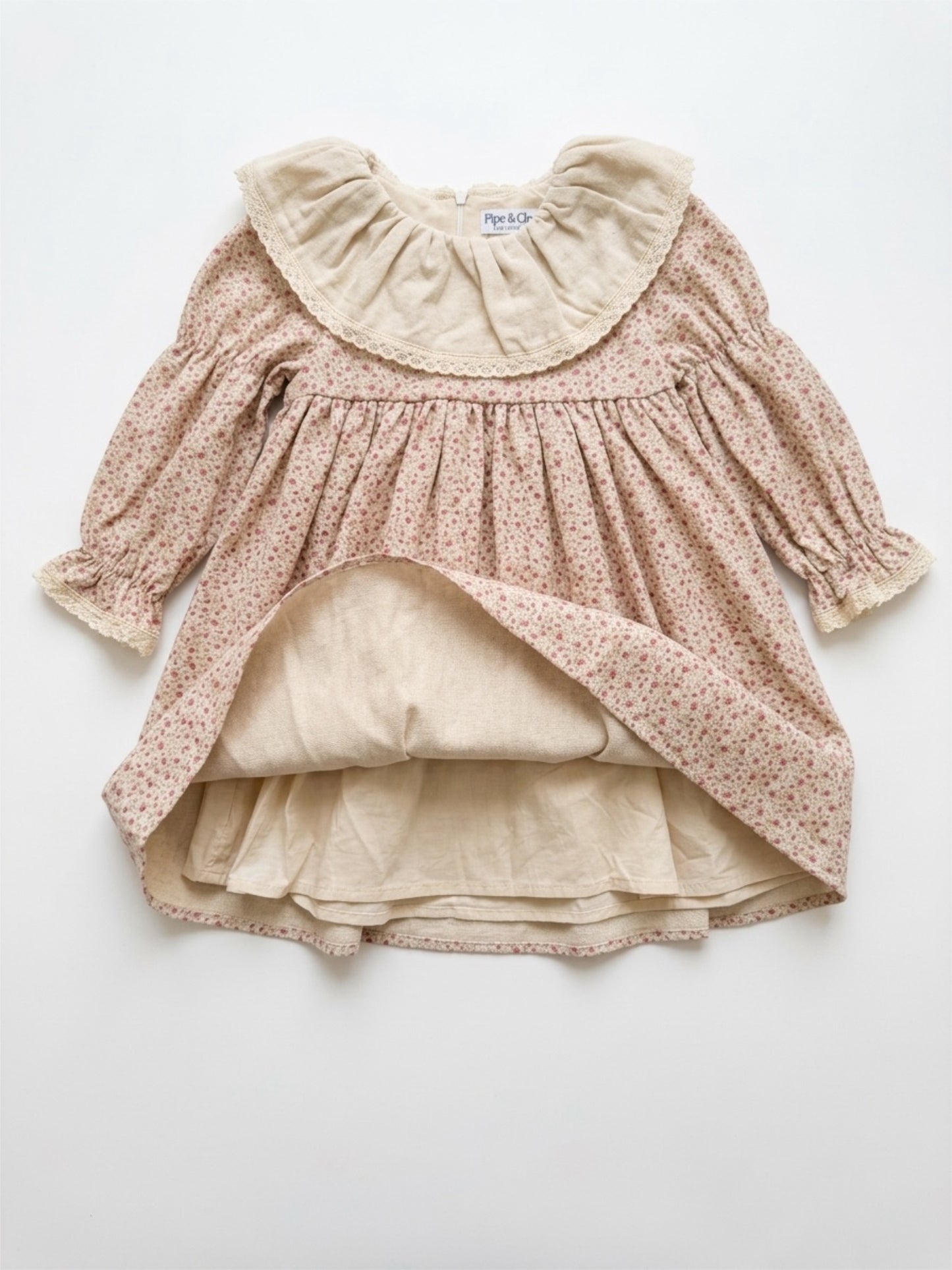 Children's dress with floral pattern and ruffled collar on a white background