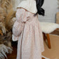 Child wearing a floral dress with a white collar in a home setting