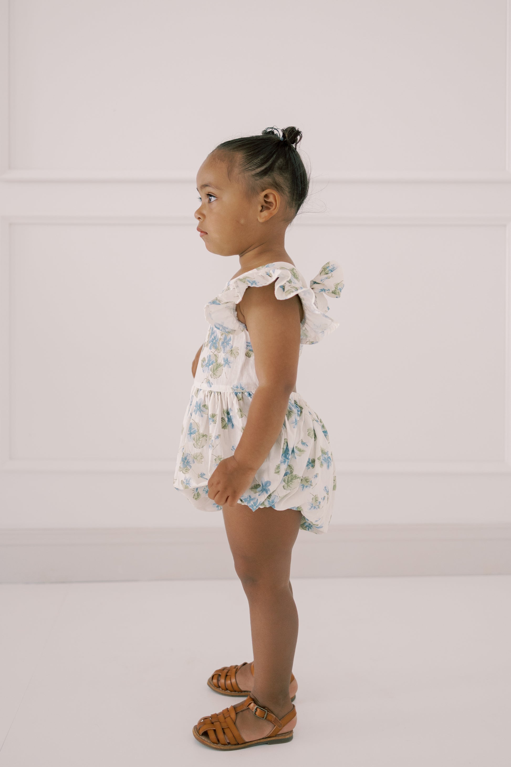 Young child wearing the Josie Bubble floral romper against a white background