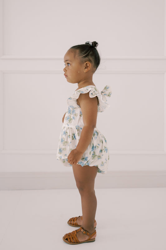 Young child wearing the Josie Bubble floral romper against a white background