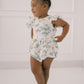 Young girl wearing a floral romper against a white background