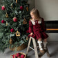 Child decorating a Christmas tree with ornaments on a ladder.