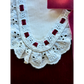 Close-up of a white lace collar with red accents on a dark background