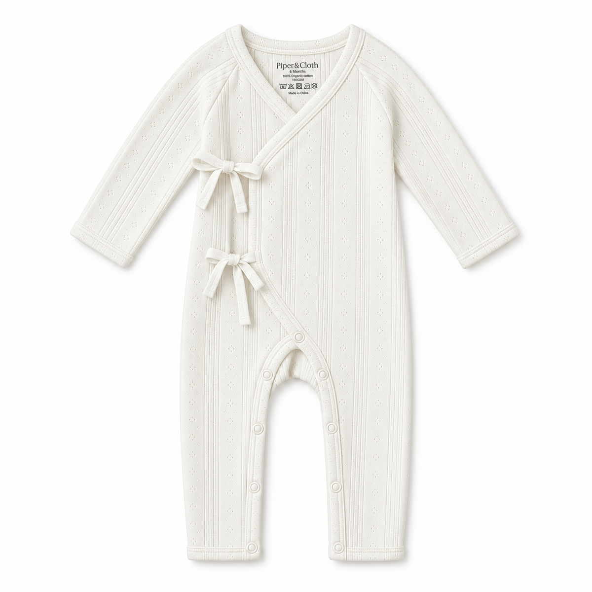 An off-white ribbed knit baby romper with long sleeves, a wrap-style front, and two small bow details, shown on a plain white background.