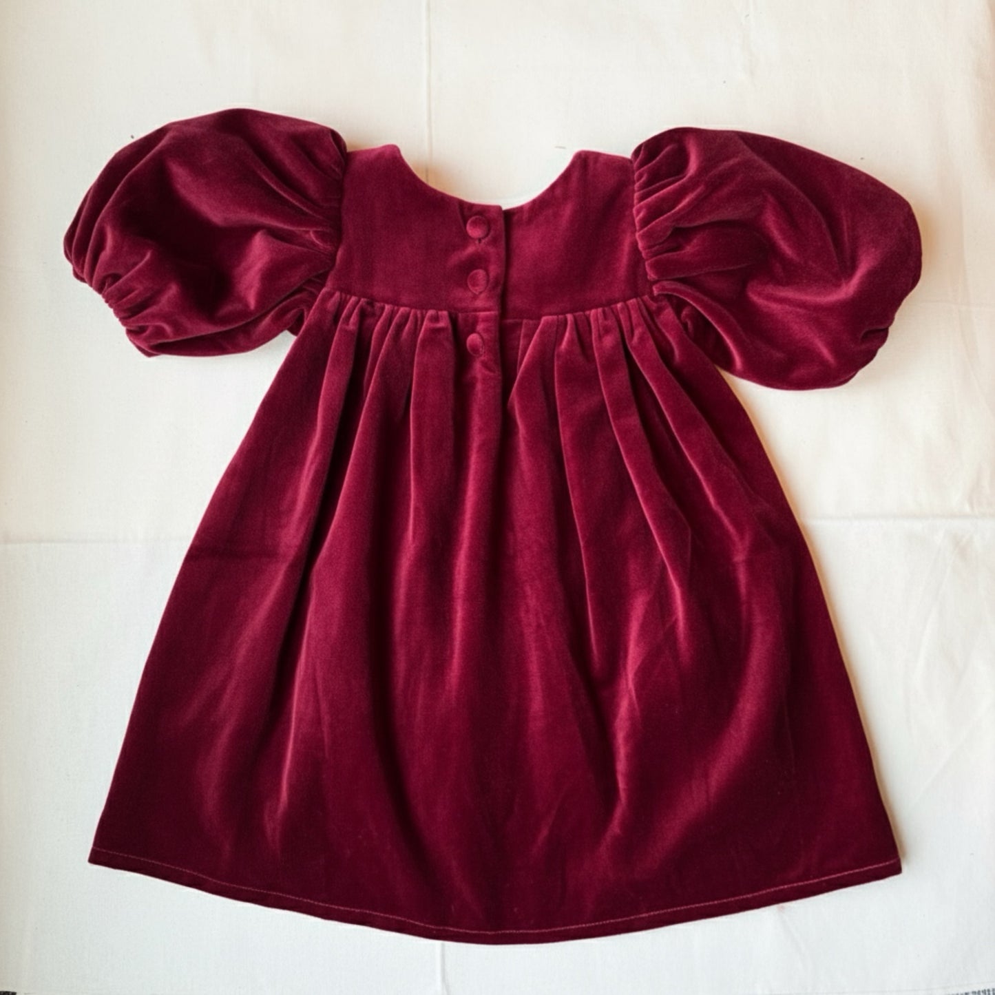 Maroon velvet dress with puff sleeves on a white background