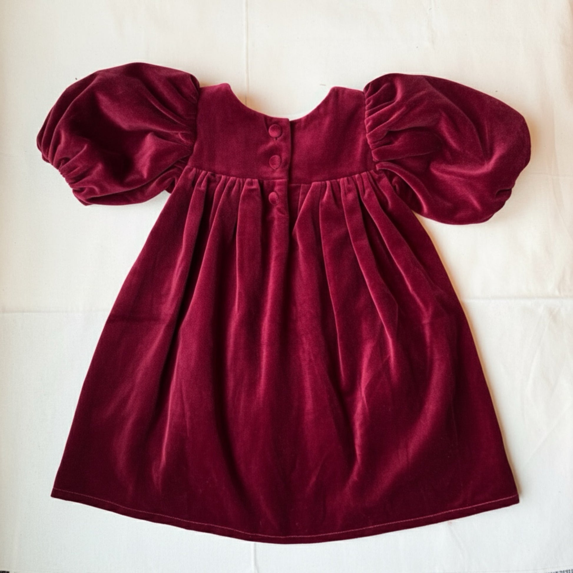 Maroon velvet dress with puff sleeves on a white background