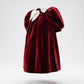 Red velvet dress with white trim on a light gray background