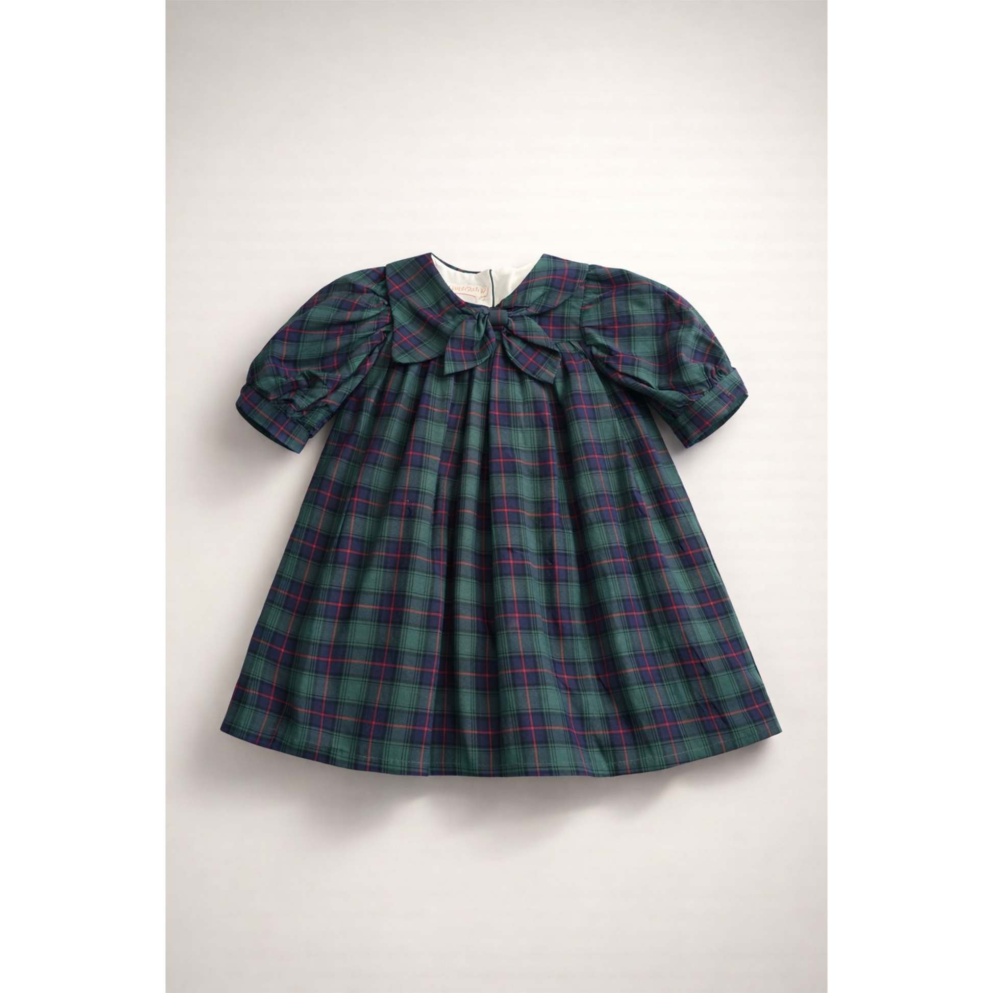 Green plaid dress with a large bow on a white background