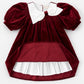 Red velvet dress with white collar and ruffled skirt on a white background
