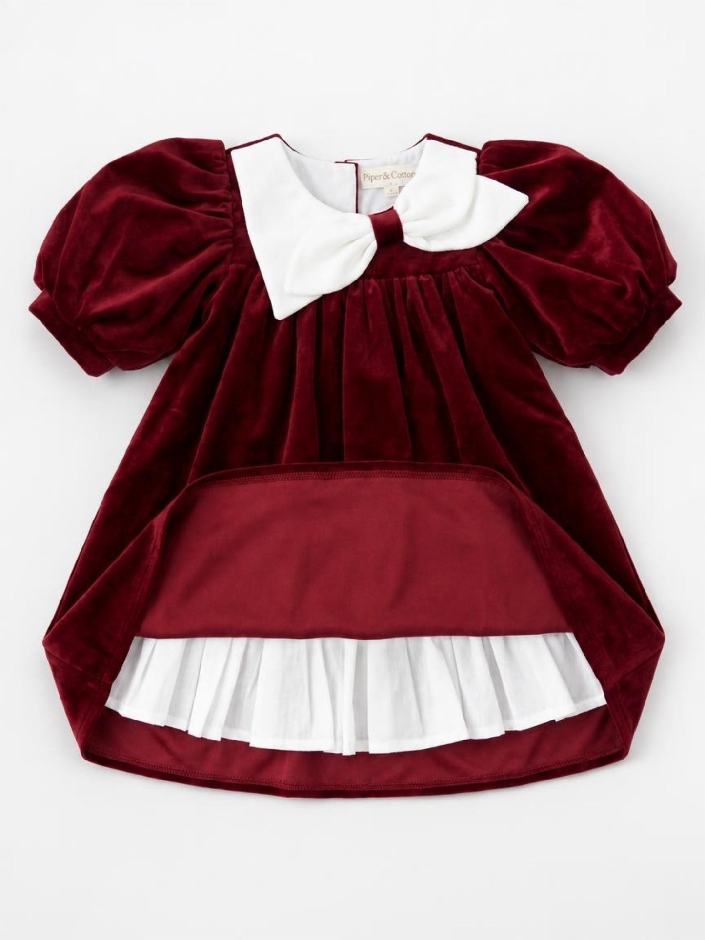 Red velvet dress with white collar and ruffled skirt on a white background