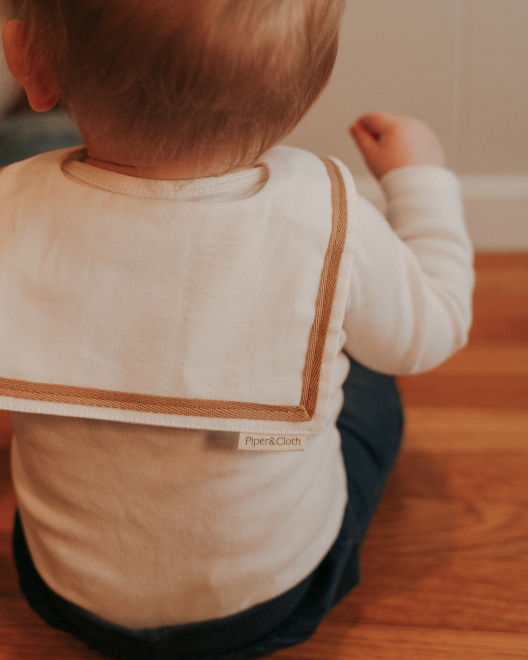 A baby wearing a White sailor-style collar bib with a knotted tie.