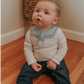 A baby wearing a navy blue sailor-style collar bib with a knotted tie in the front.