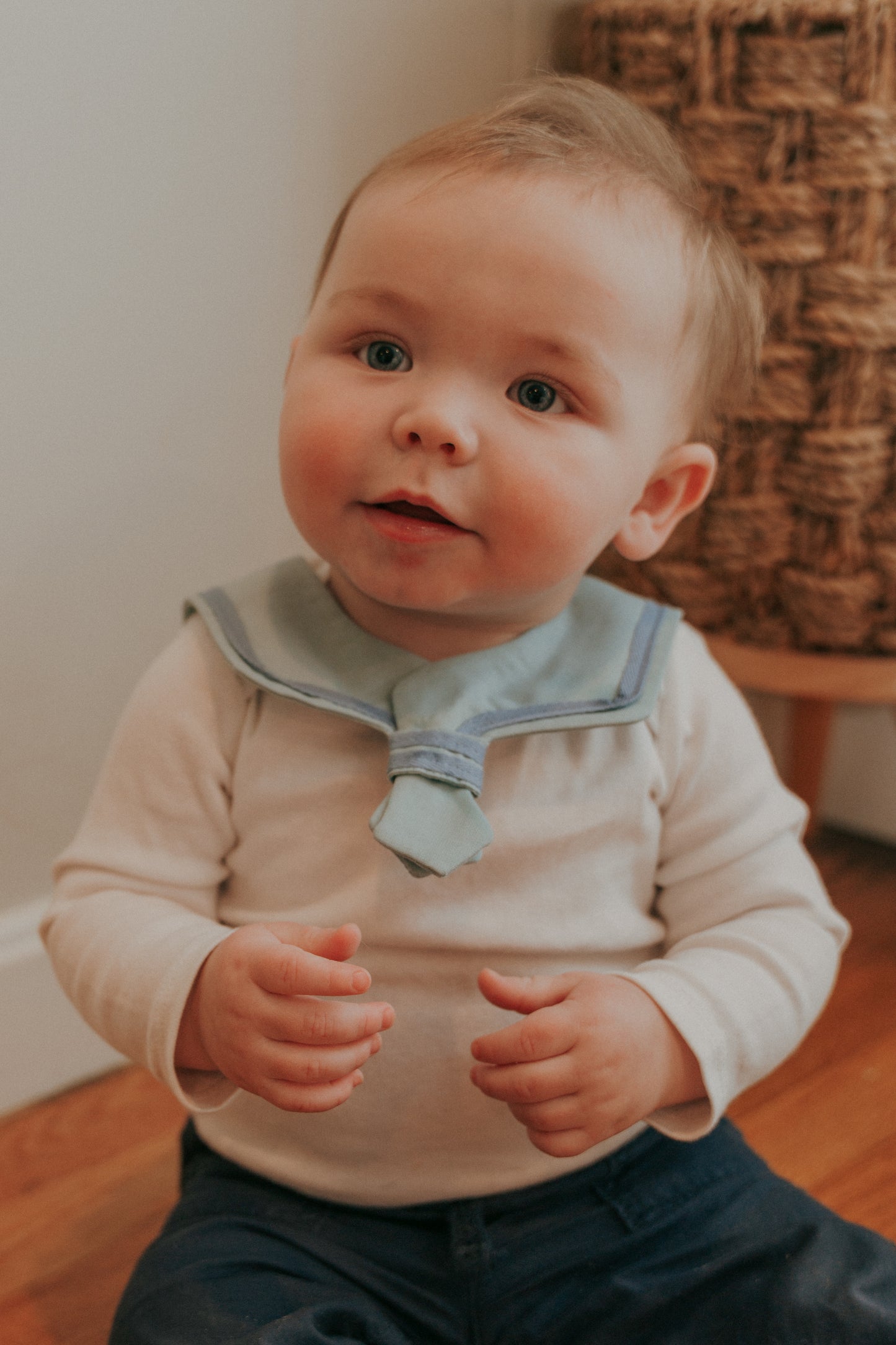 A baby wearing a navy blue sailor-style collar bib with a knotted tie in the front.