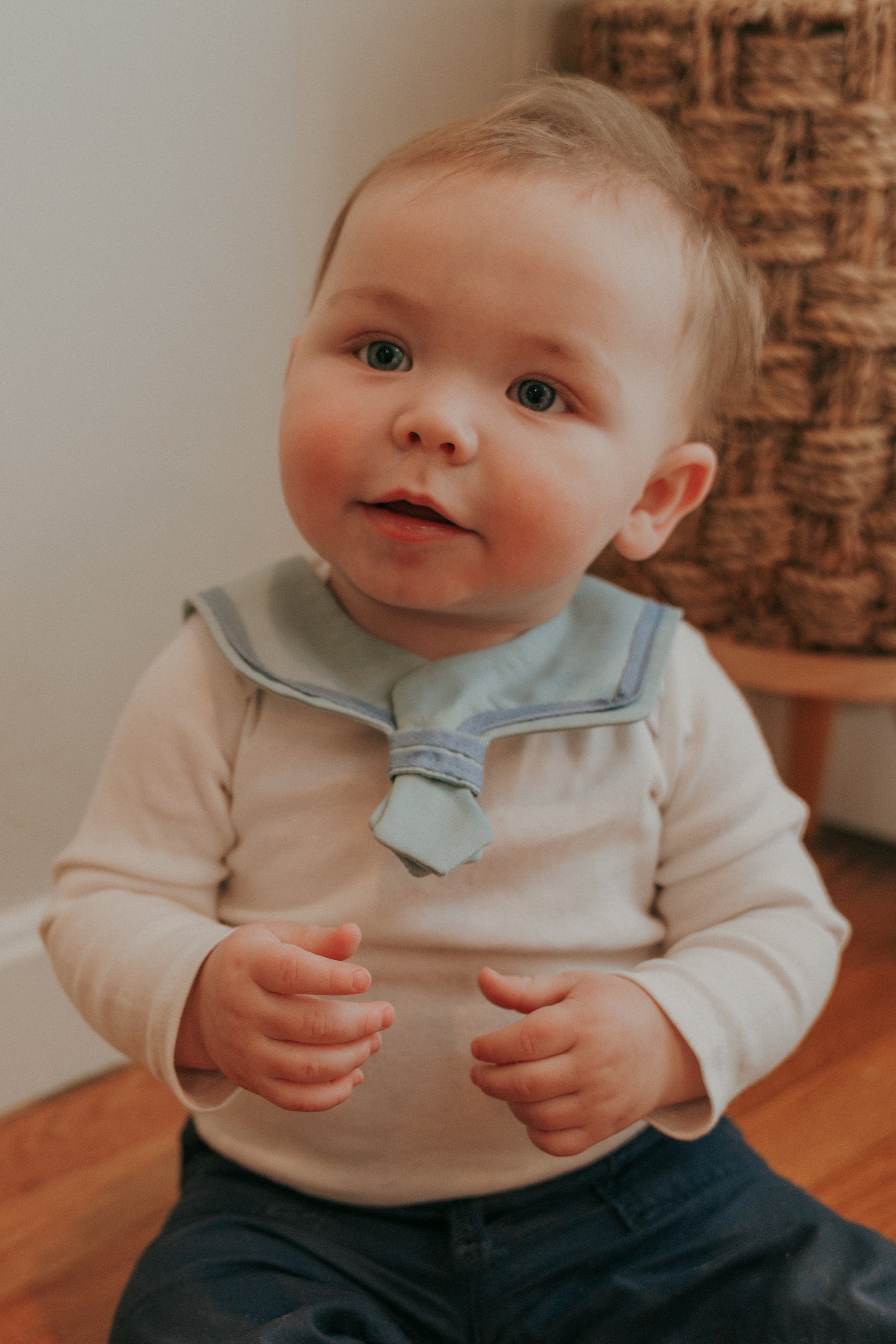 A baby wearing a navy blue sailor-style collar bib with a knotted tie in the front.