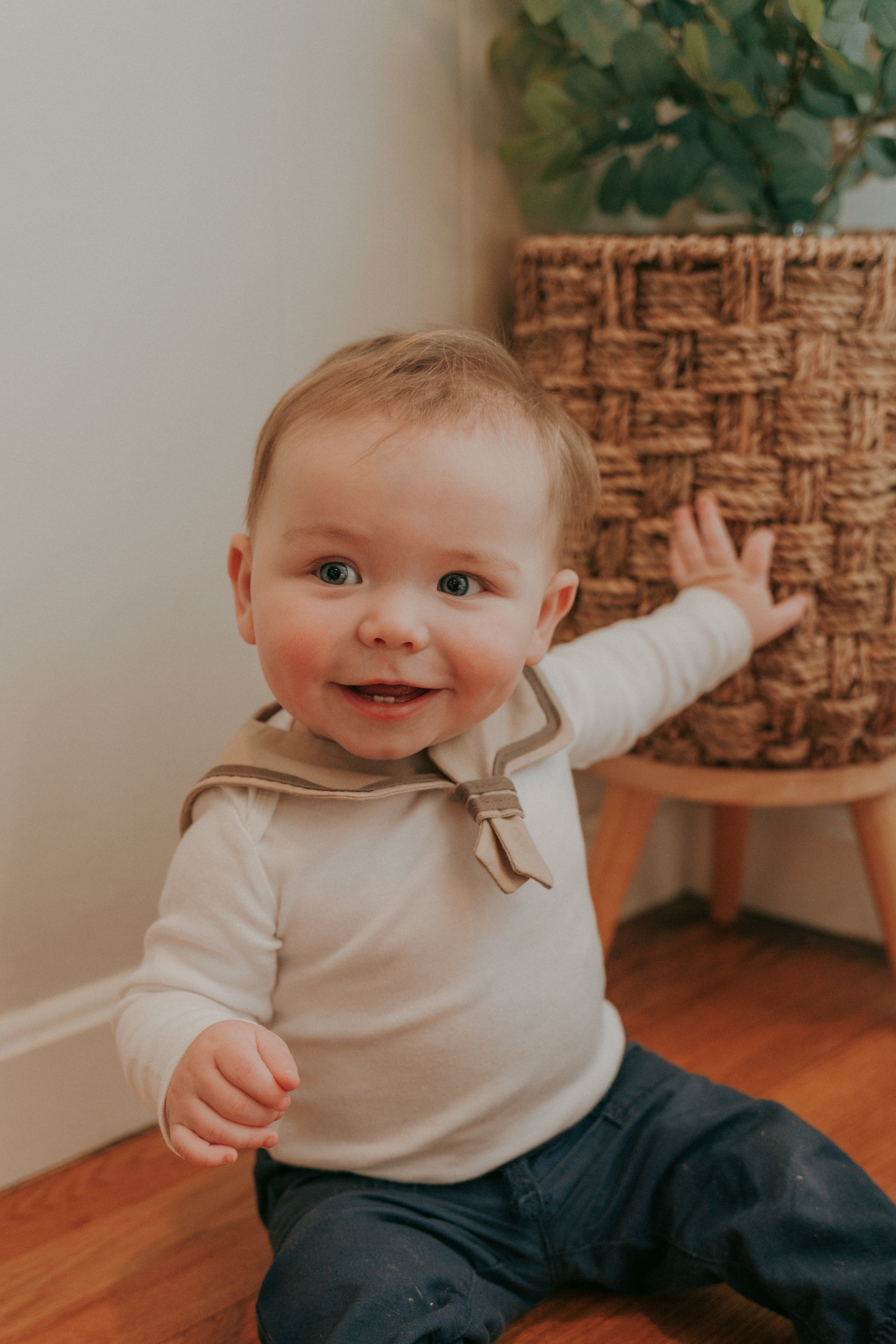 A baby wearing a brown sailor-style collar bib with a knotted tie.