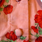 Close-up of a pink fabric with red floral patterns and buttons.
