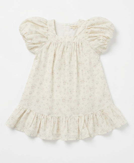 White baby dress with ruffled sleeves on a light gray background