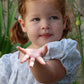 Young girl in a light blue dress holding out her hand in a garden setting