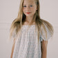 Young girl wearing a light blue floral dress against a plain background