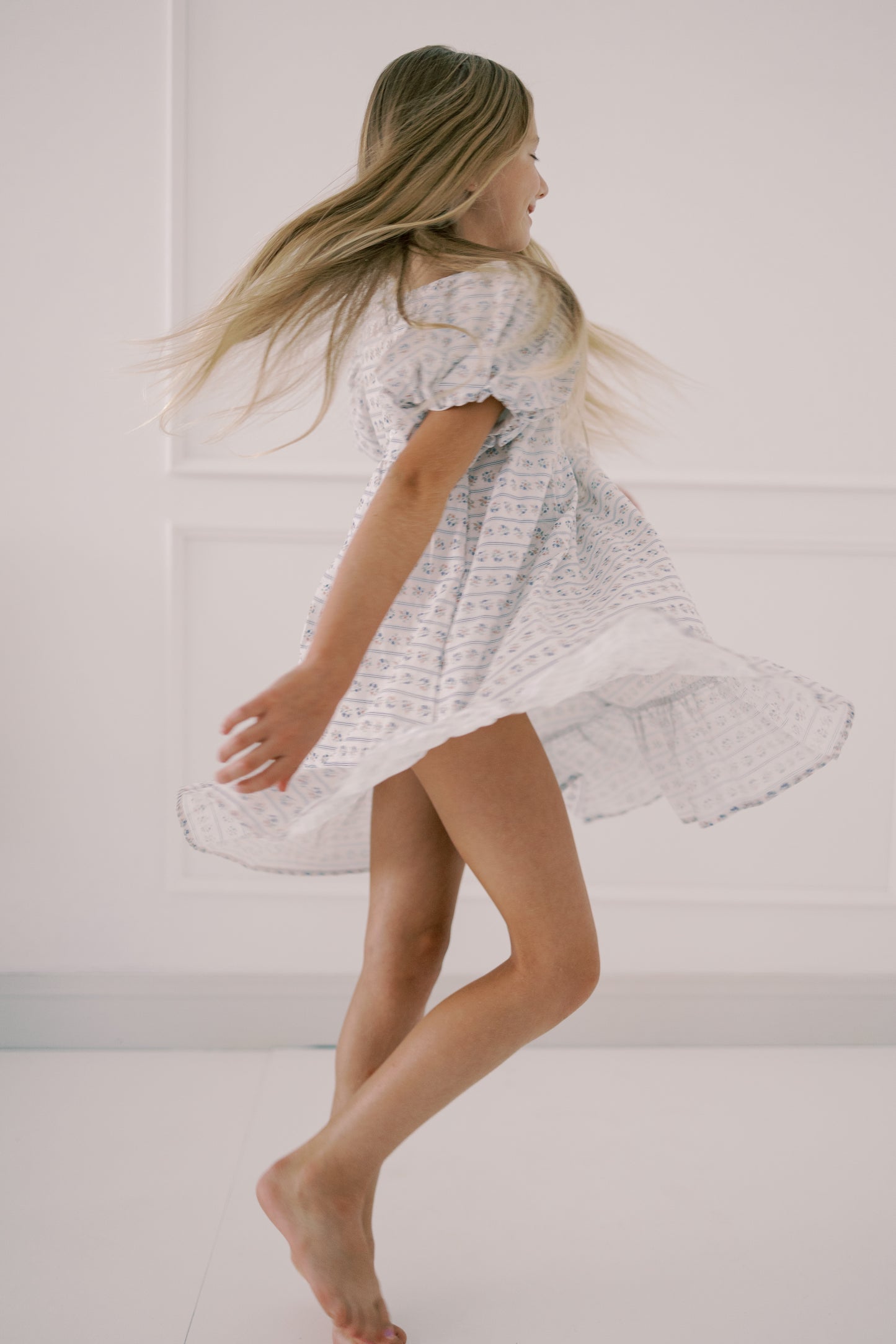 Girl in a white dress standing against a plain background