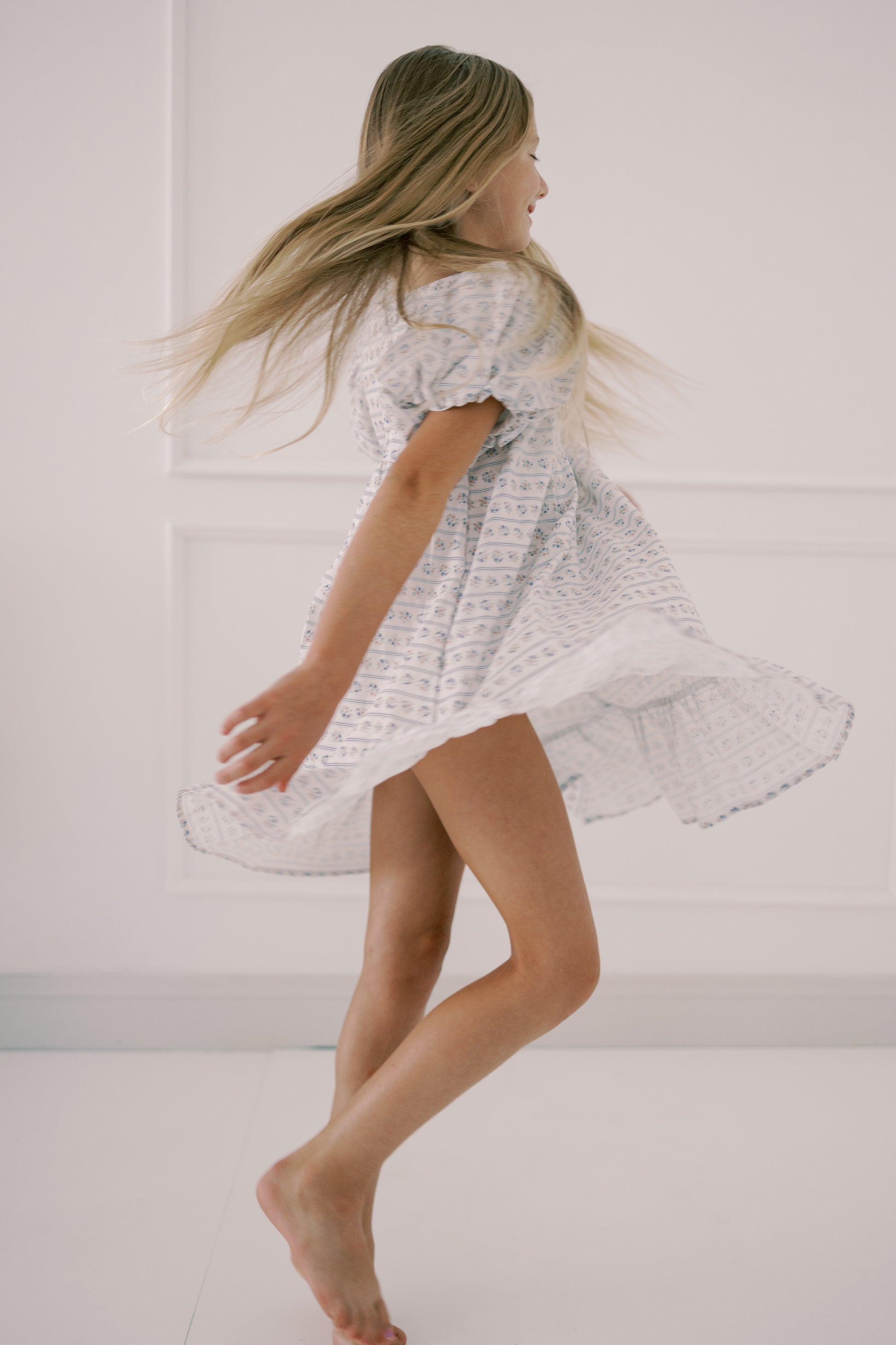 Girl in a white dress standing against a plain background