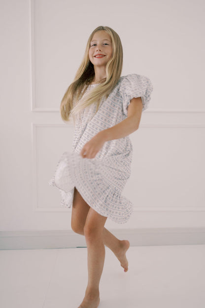 Girl  a white textured dress against a plain background