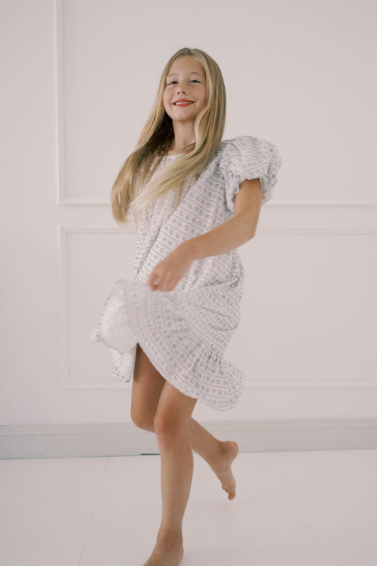 Girl  a white textured dress against a plain background