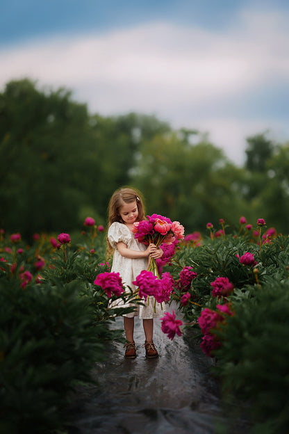 Young girl holding flowers in a garden with a blurred background