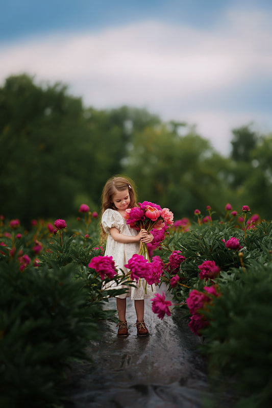 Young girl holding flowers in a garden with a blurred background