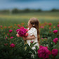 Young girl holding pink flowers in a field of flowers