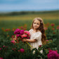 Young girl holding flowers in a field of pink and purple flowers with a blurred background