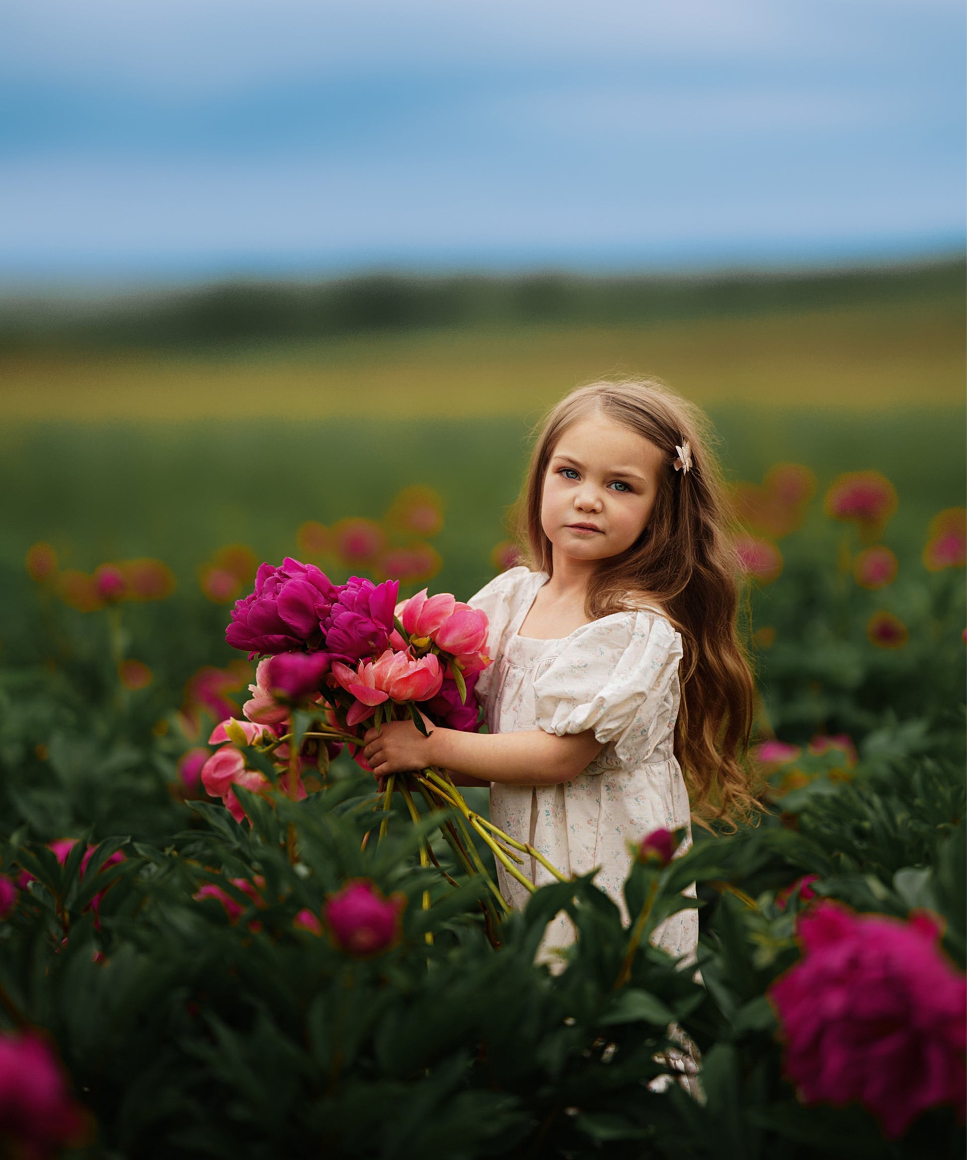 Young girl holding flowers in a field of pink and purple flowers with a blurred background